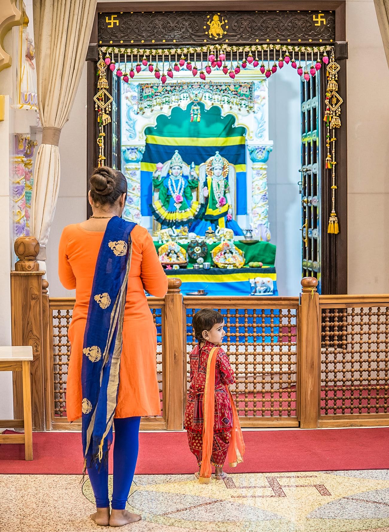 Community: (clockwise from far left) ladies chant together; local students pass by the Shree Shiva Shakti Temple in Zanzibar; an altar is draped in the Tanzanian flag; a temple nestled among Dar es Salaam’s high-rises; priest Lakshmi Narasimha Rajagopal Iragavarapu serves at the Shree Sanatan Dharma Sabha